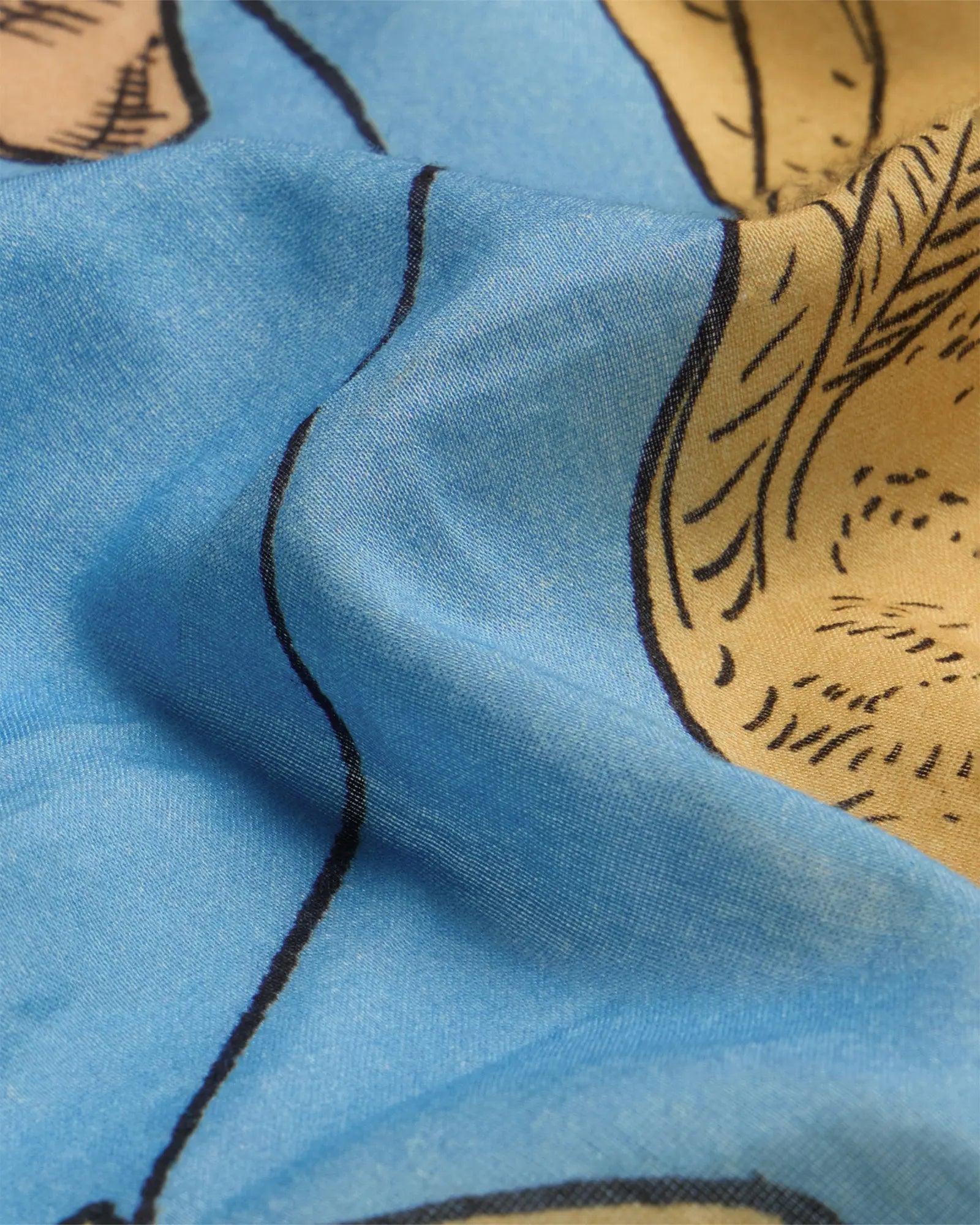 Close-up of light blue scarf with parrot and cat illustrations