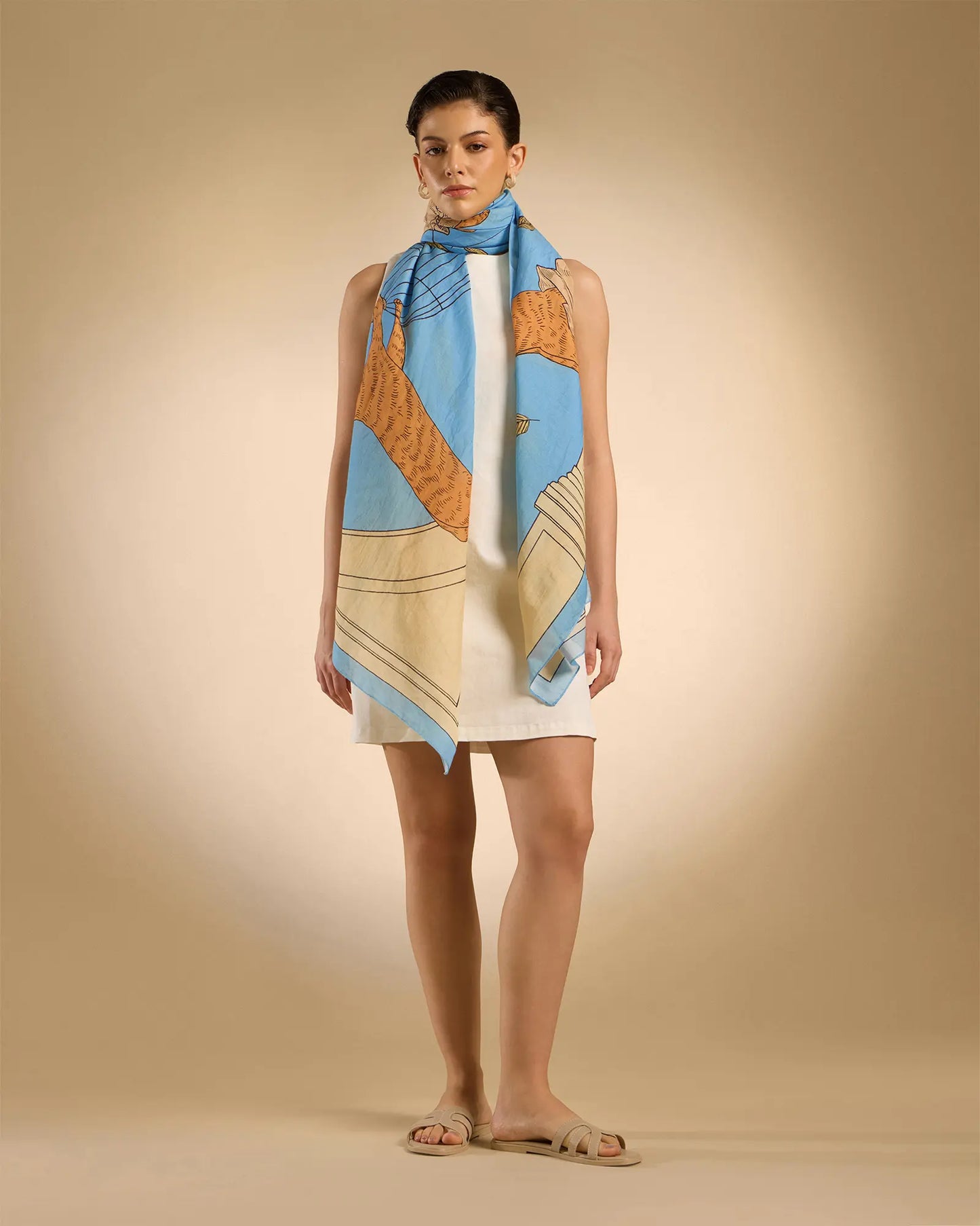 Woman model wearing Illustrated light blue rectangle scarf with classical design featuring a cat, parrots and pillars 